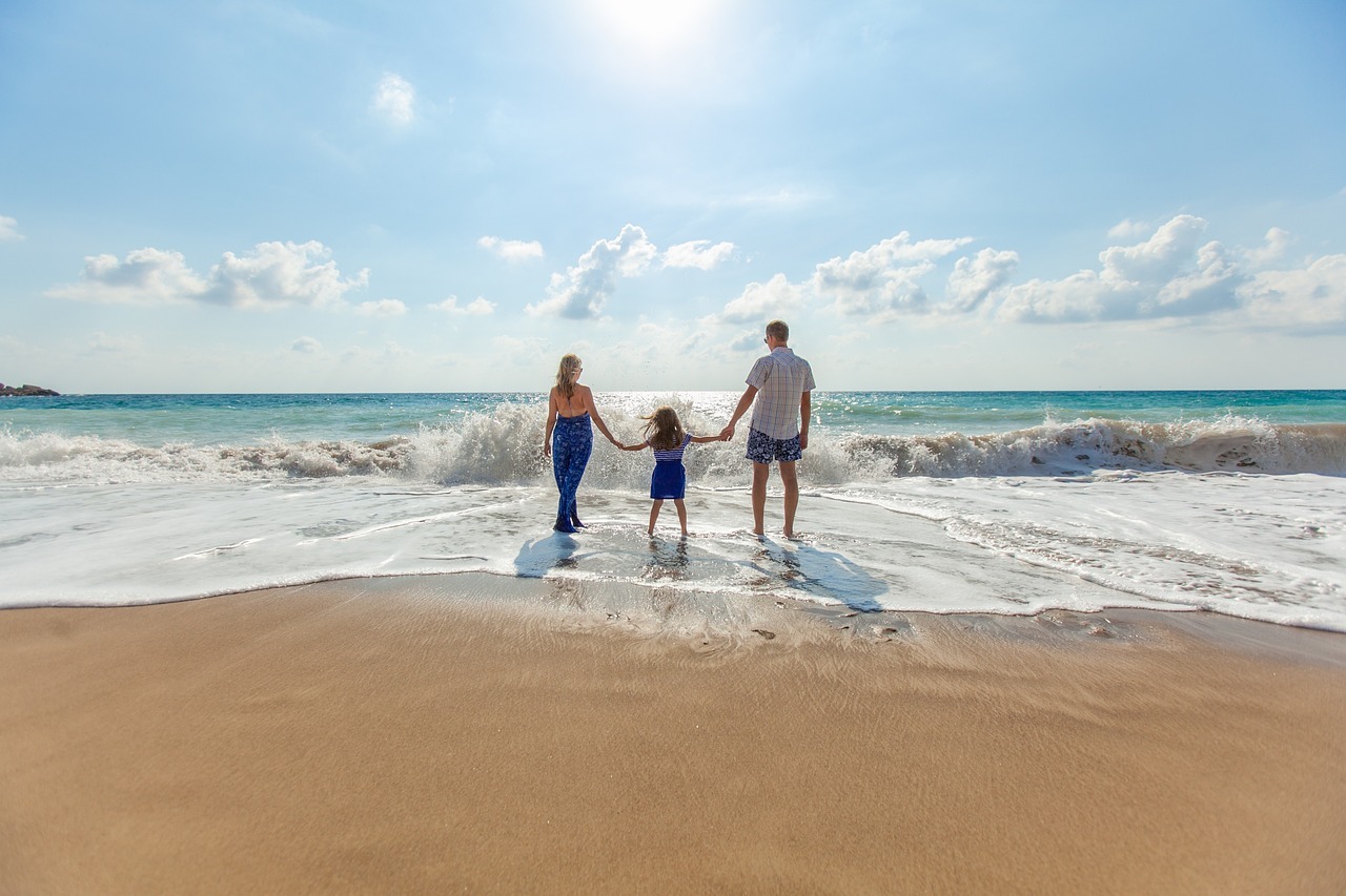 Fotografia di giovani genitori con figlia sulla spiaggia davanti al mare